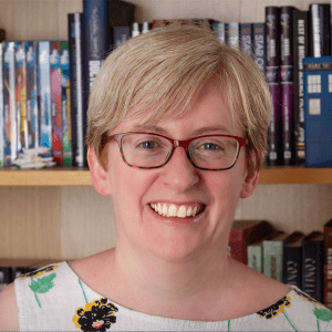 Headshot of Una McCormack, the author known for her work on Una McCormack Star Trek Doctor Who novels, in front of a sci-fi bookshelf